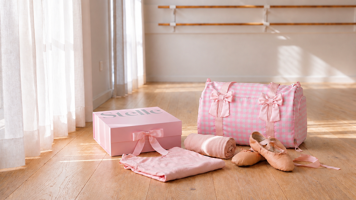 Ballet gift ideas for young dancers: wrapped gift box with a pink ribbon beside a kids leotard, tights, ballet shoes, and dance bag