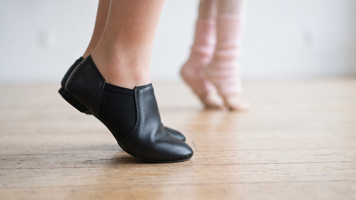 Black slip-on jazz dance shoes pivoting on a studio floor