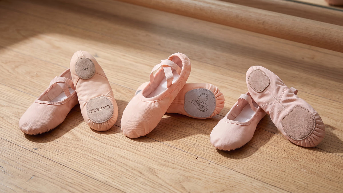 Three split-sole canvas ballet slippers for adult beginners laid side by side on a studio floor for comparison