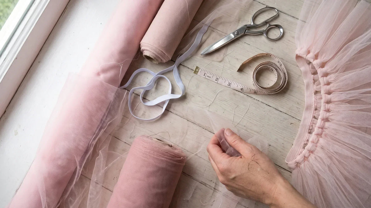 Tulle rolls, elastic and scissors beside a half-finished pink no-sew tutu