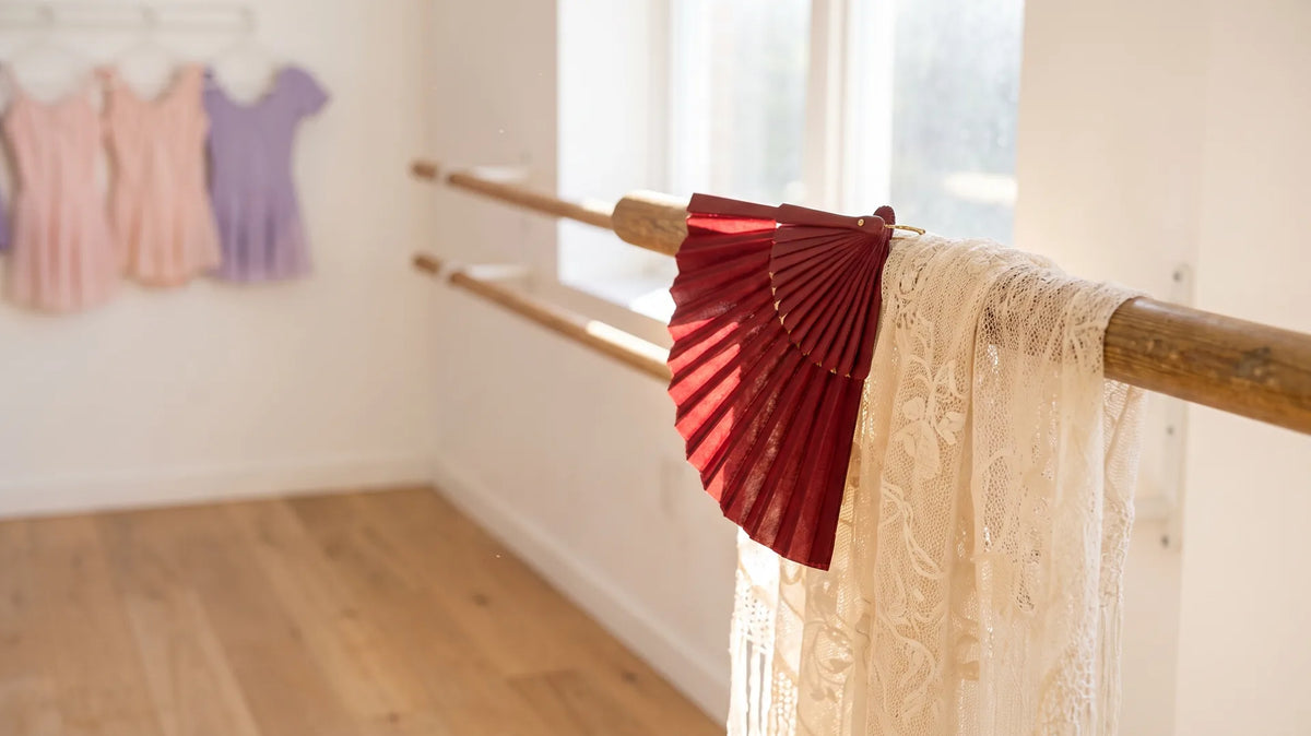 Red fan and lace shawl on a ballet barre evoking Don Quixote's Spanish setting