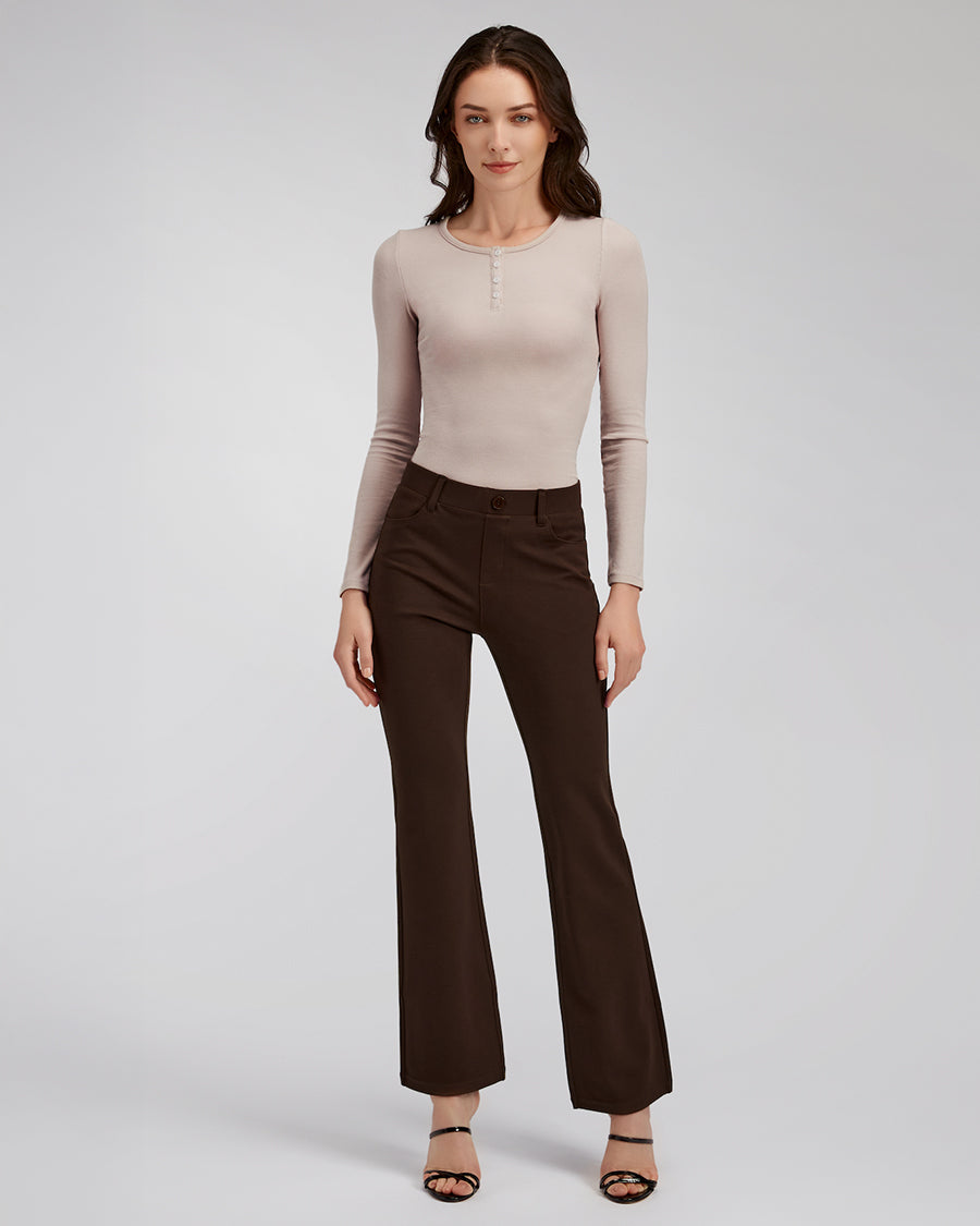 Woman wearing a beige long-sleeve top and brown flared pants on a light gray background
