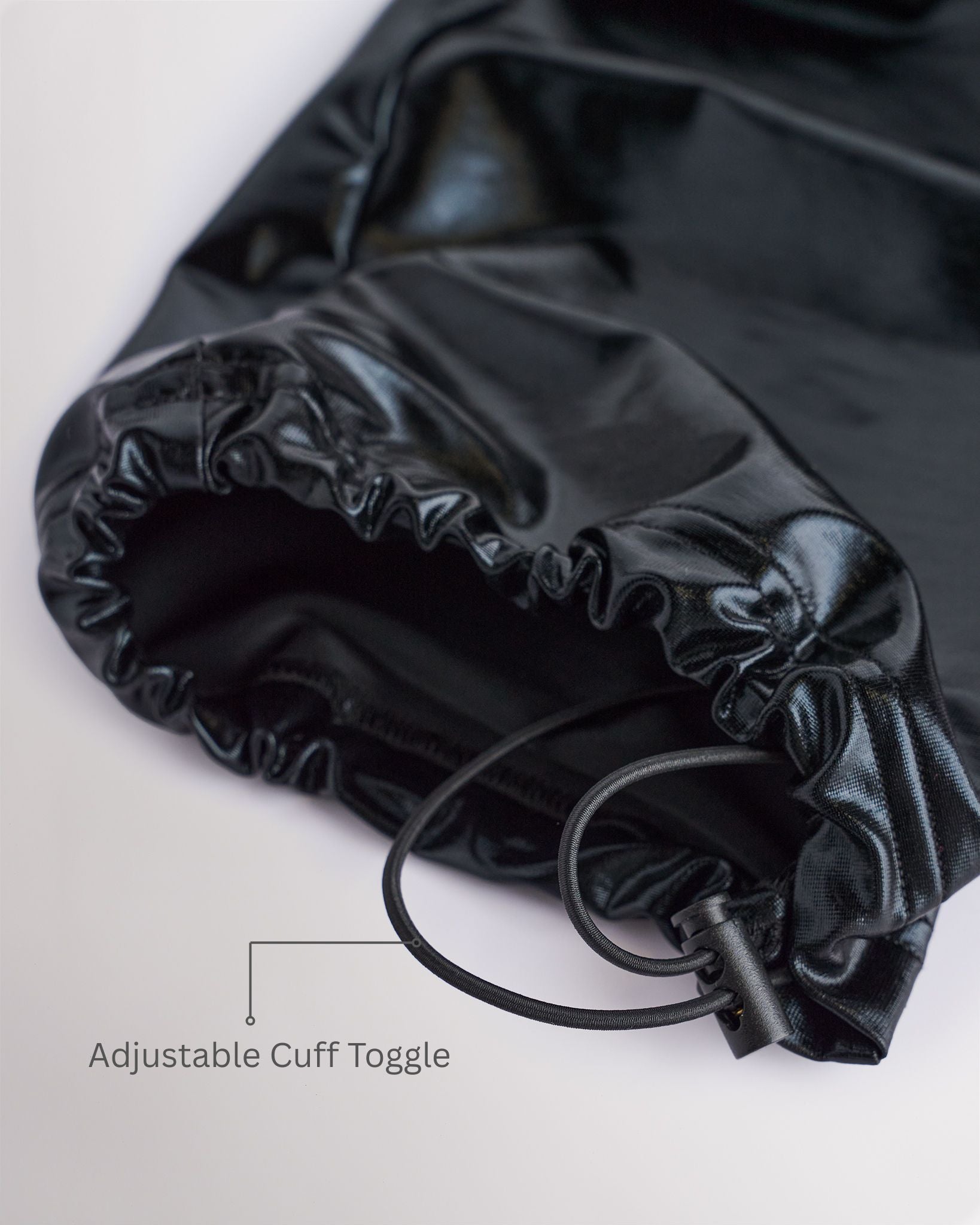 Close-up of patent black girls cargo pants showing the adjustable cuff toggle at the hem for switching between wide-leg and tapered jogger styling.