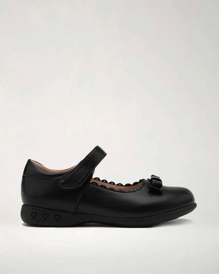 A black Mary Jane style flat dress shoe with a strap and decorative mini bows on the toe and hearts on the sole.