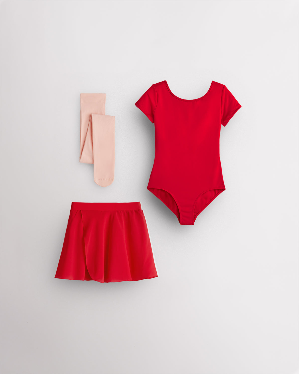 Red girls ballet starter kit laid flat with short sleeve leotard, red chiffon pull-on skirt, and ballet pink footed tights.