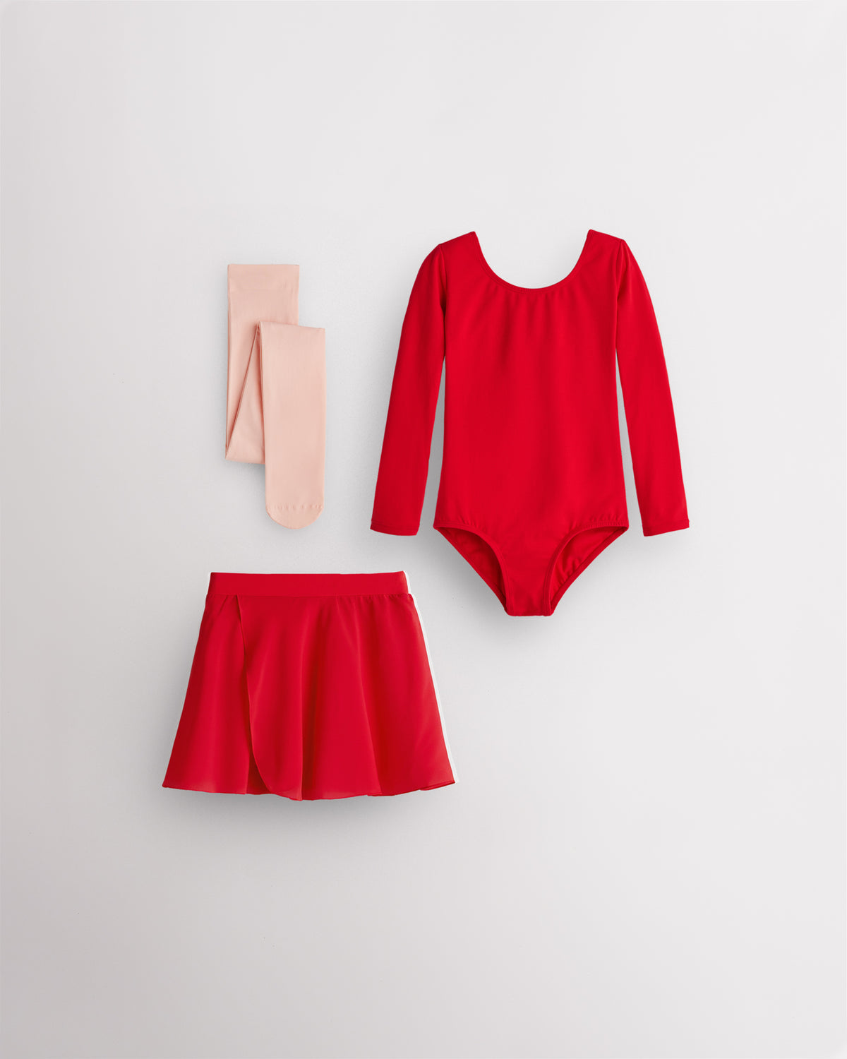 Red girls ballet starter kit laid flat with long sleeve leotard, pull-on skirt, tie skirt, and ballet pink footed tights.