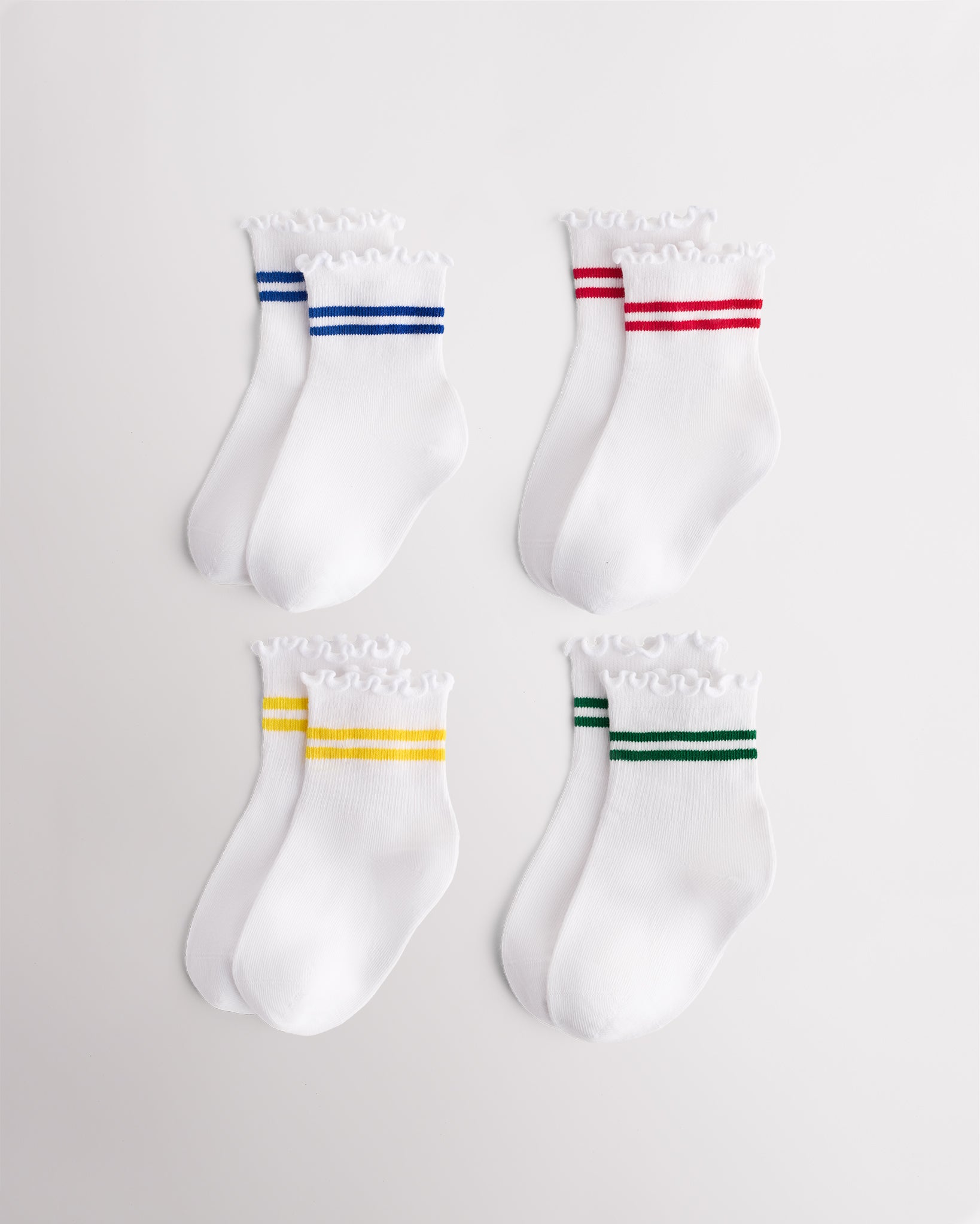 Four pairs of white kids socks with blue, red, yellow, and green sporty stripes and lettuce-edge ruffle cuffs