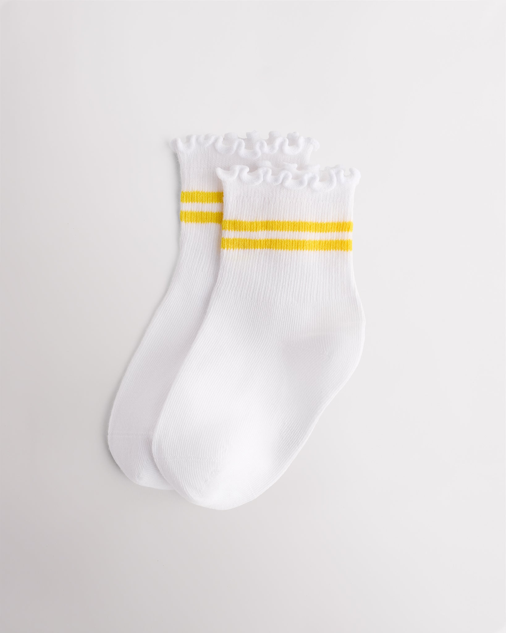 White kids socks with yellow sporty stripes, ribbed cuffs, and lettuce-edge ruffle trim