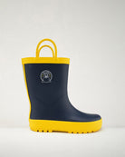 Navy and yellow rain boot with a logo on a light gray background