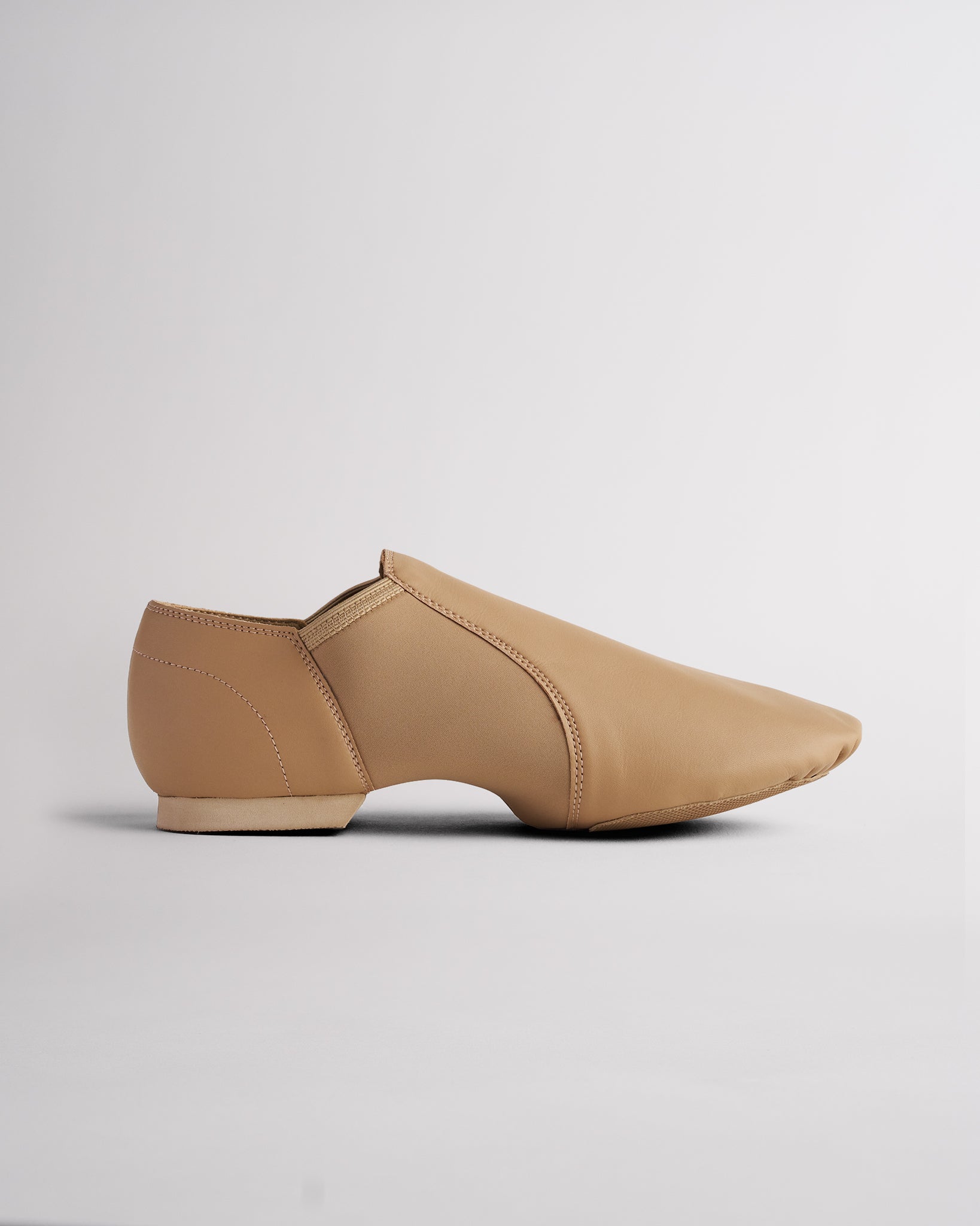 Tan adult vegan leather jazz shoe with easy slip-on style, flexible neoprene arch, and low heel.