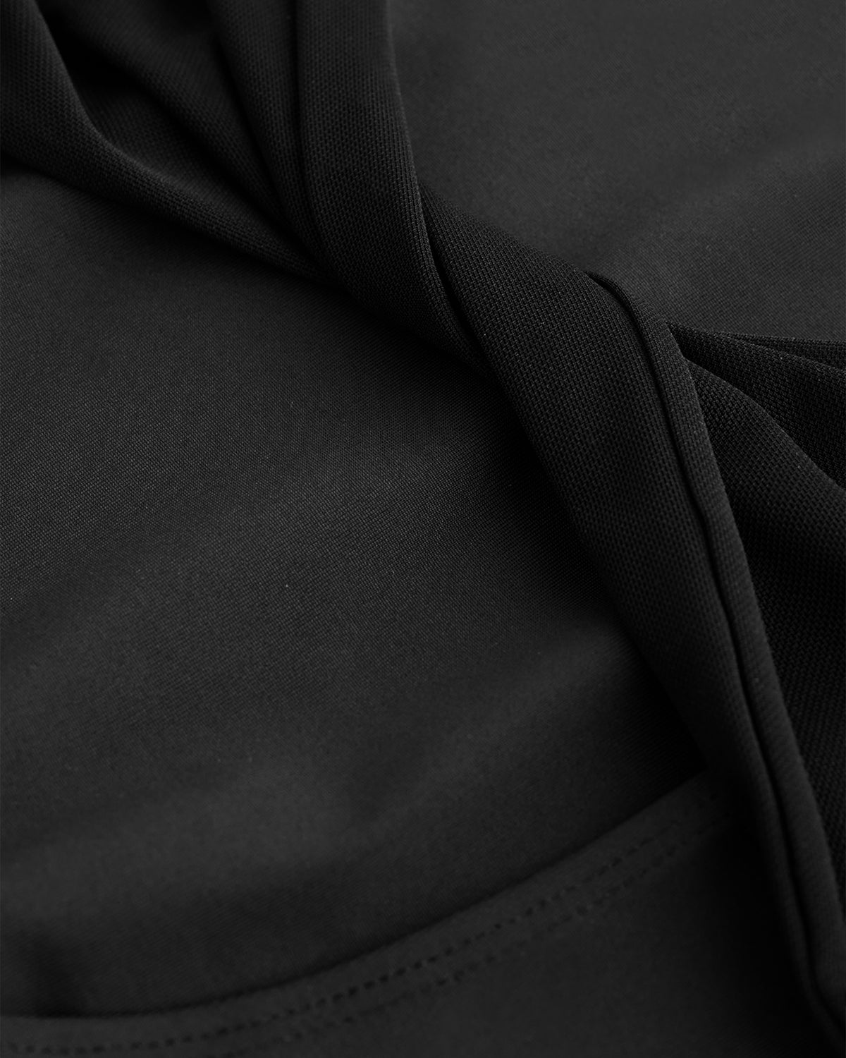 Close-up of Black performance leotard showing soft stretch fabric and twisted mesh back detail.