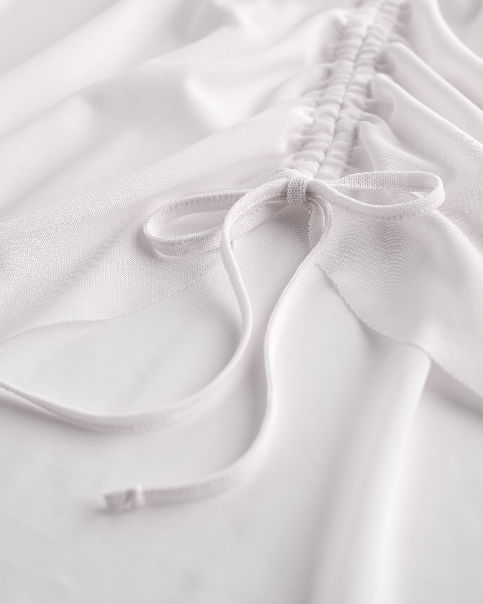 Close-up of white mesh ballet skirt showing adjustable ruched drawstring and soft sheer fabric.