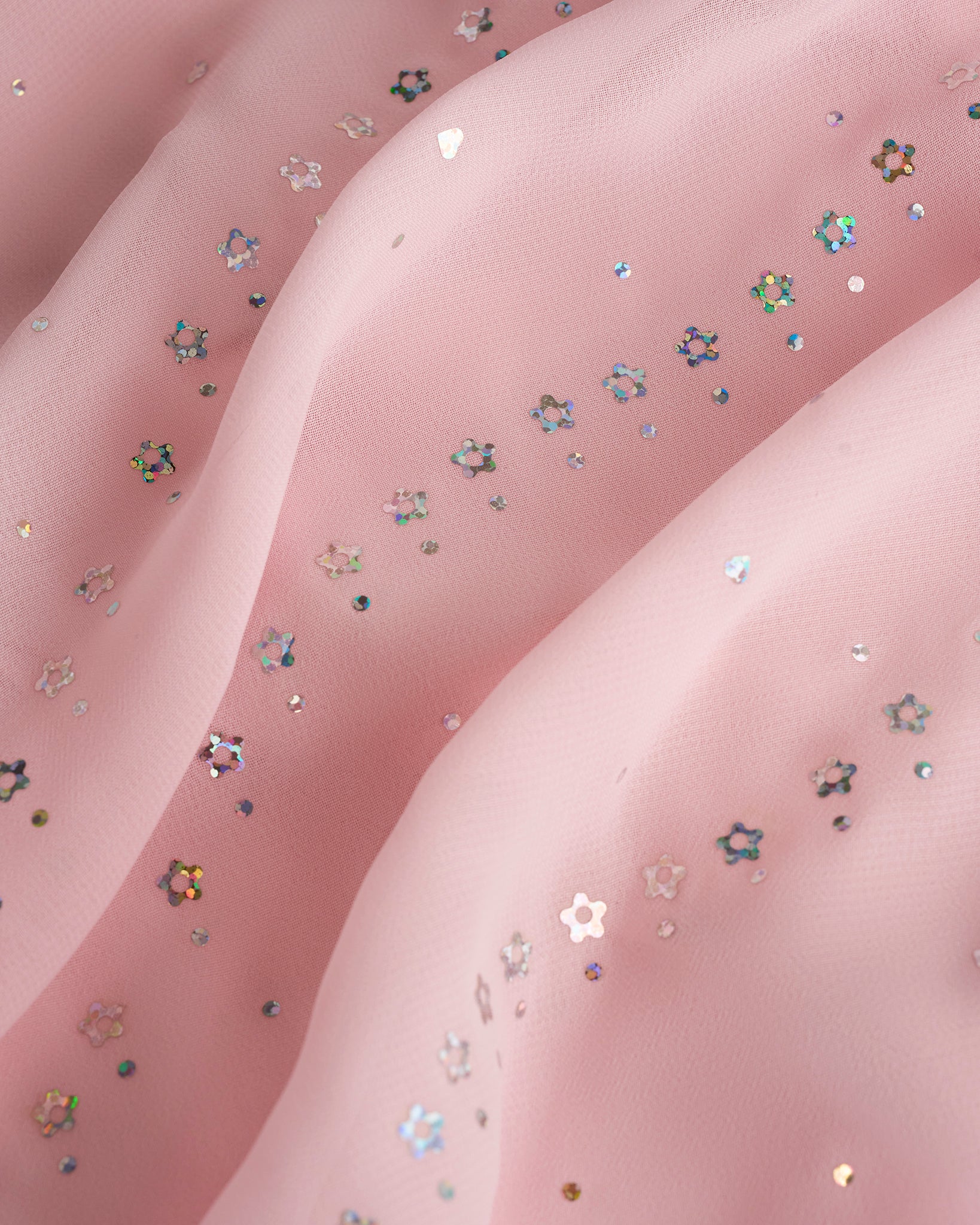 Close-up of ballet pink dance dress fabric with sparkling floral sequins on chiffon for a playful ballet performance look.
