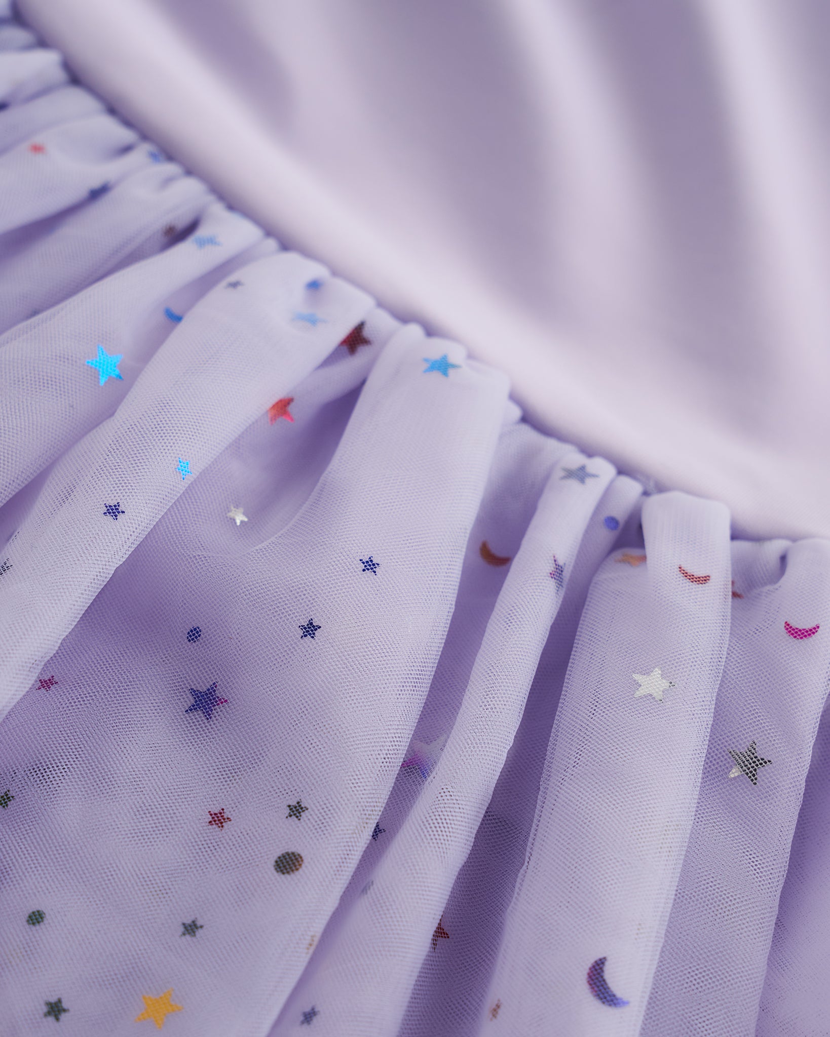 Close-up of lavender tutu dress skirt showing multicolor celestial sequins, layered mesh, and star and moon details.