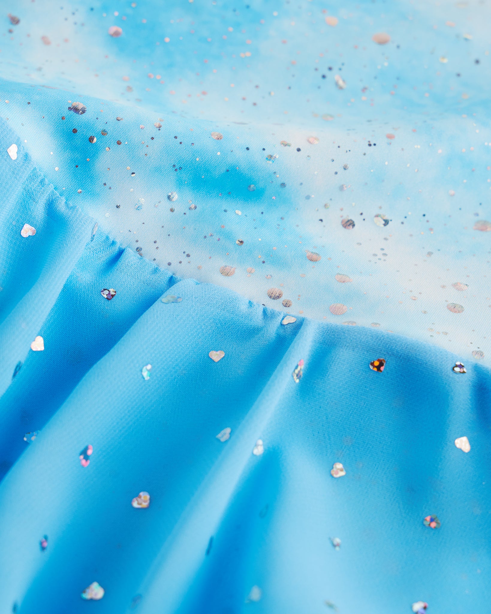Close-up of Cloudburst Blue sequin dress fabric showing shimmer details, printed bodice, and layered chiffon skirt.