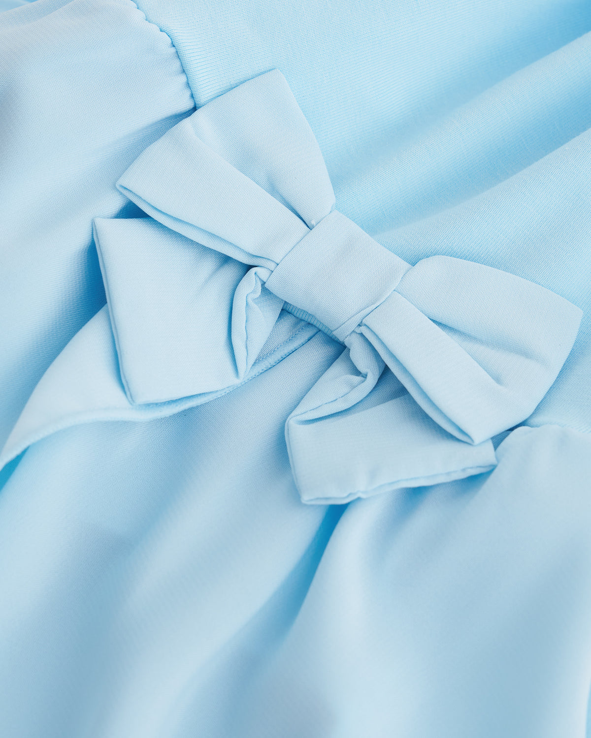 Close-up of blue ballet dress showing the decorative bow accent and soft chiffon wrap skirt.