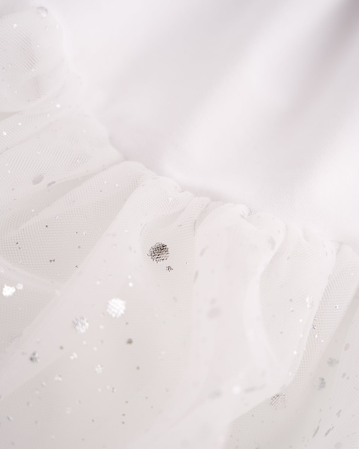 Close-up of White mesh skirt showing soft layered fabric and subtle shimmer details.
