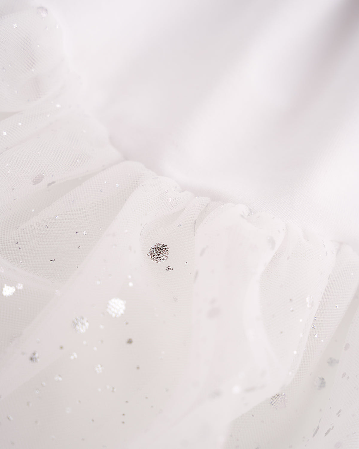 Close-up of White mesh skirt showing soft layered fabric and subtle shimmer details.