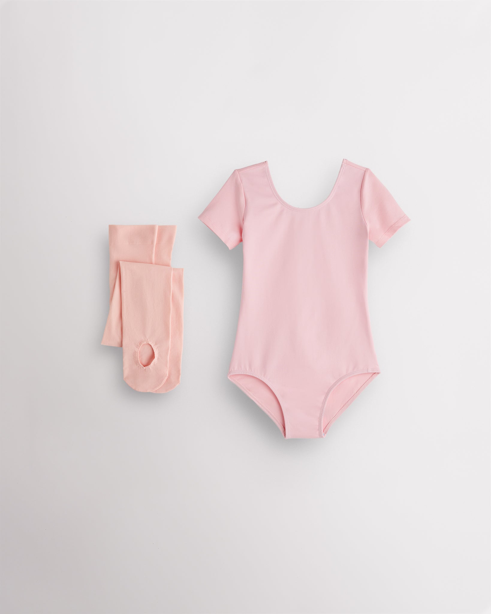 Ballet Pink short sleeve leotard with pink convertible dance tights laid flat for girls ballet and dance class.