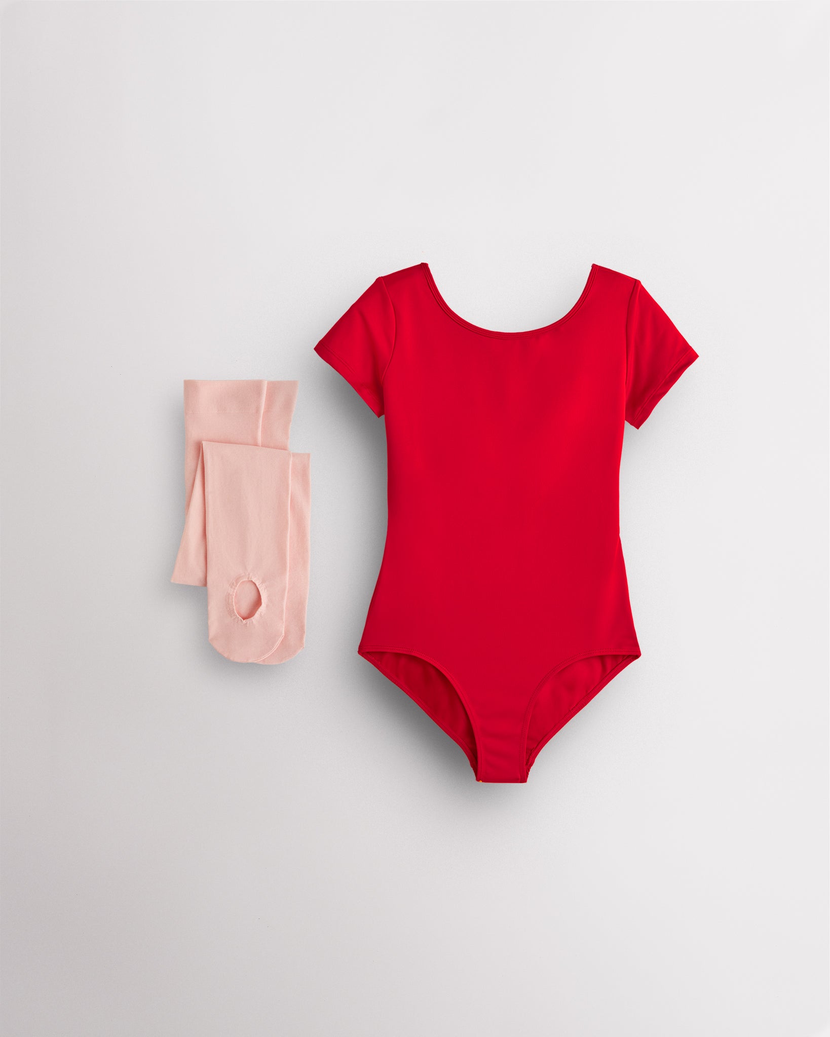 Red short sleeve leotard with pink convertible dance tights laid flat for girls ballet and dance class.