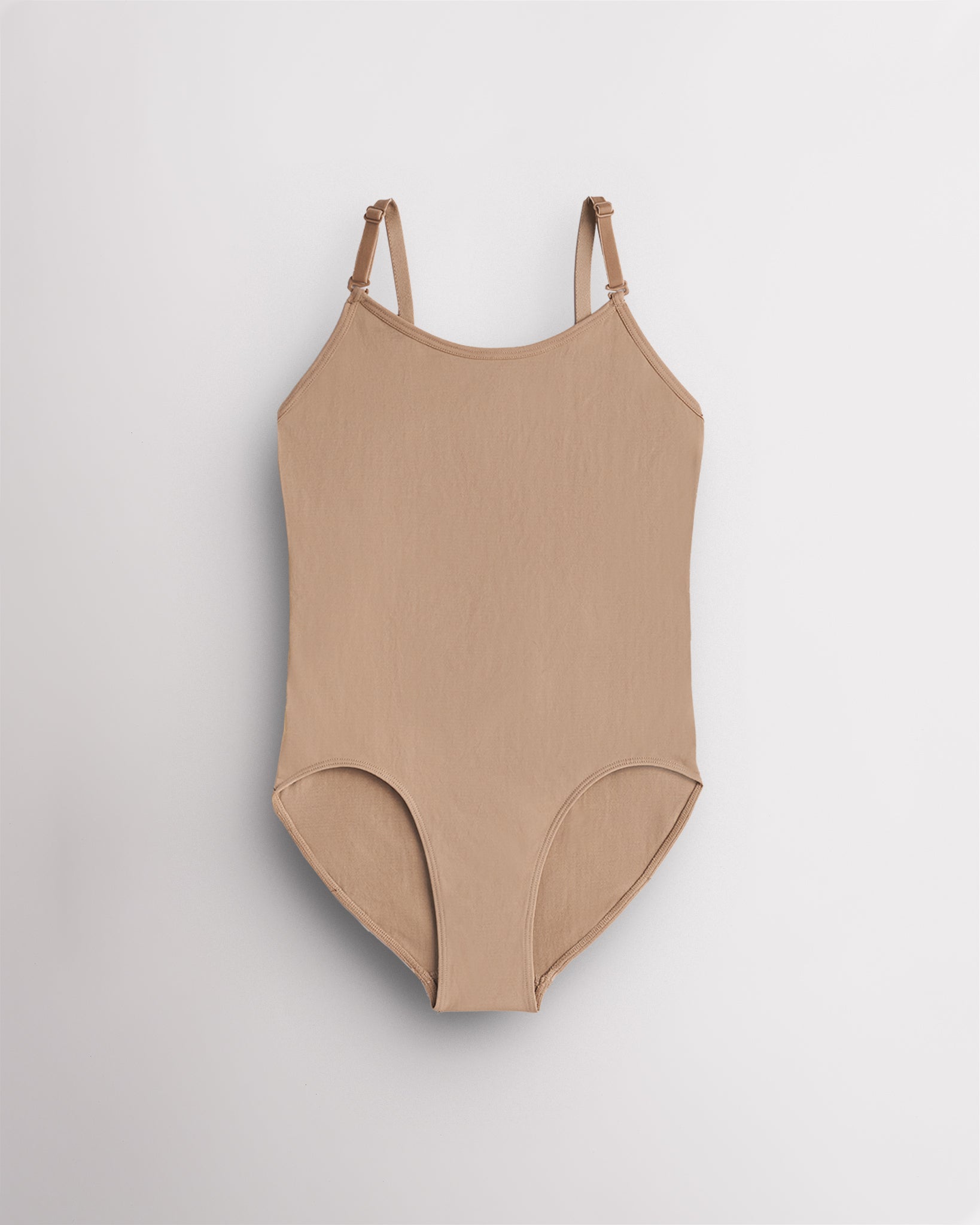 Nude seamless camisole girls leotard with scoop neckline, adjustable straps, and smooth ballet base-layer design.