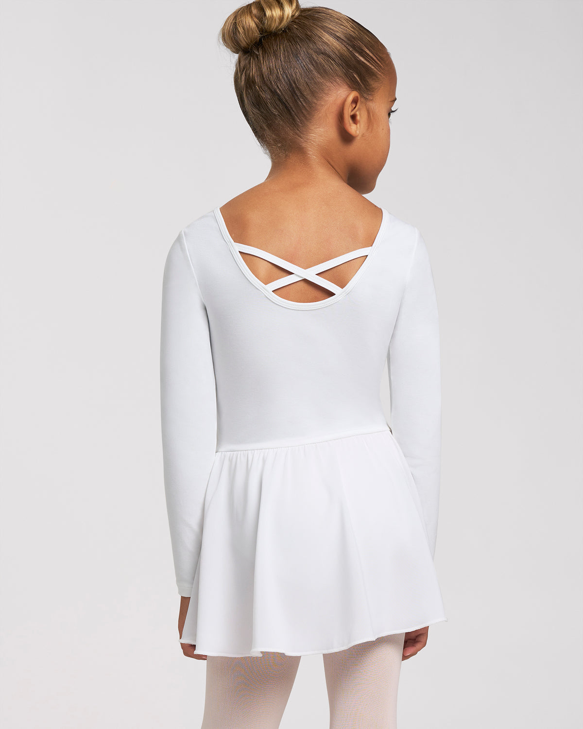 Back view of girl wearing a white ballerina dress with long sleeves, crisscross back detail, and attached chiffon wrap skirt.