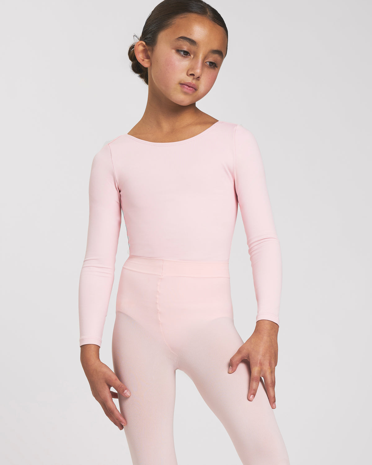 Girl wearing a Ballet Pink long sleeve ballet leotard with round neckline, fitted silhouette, and front lining.