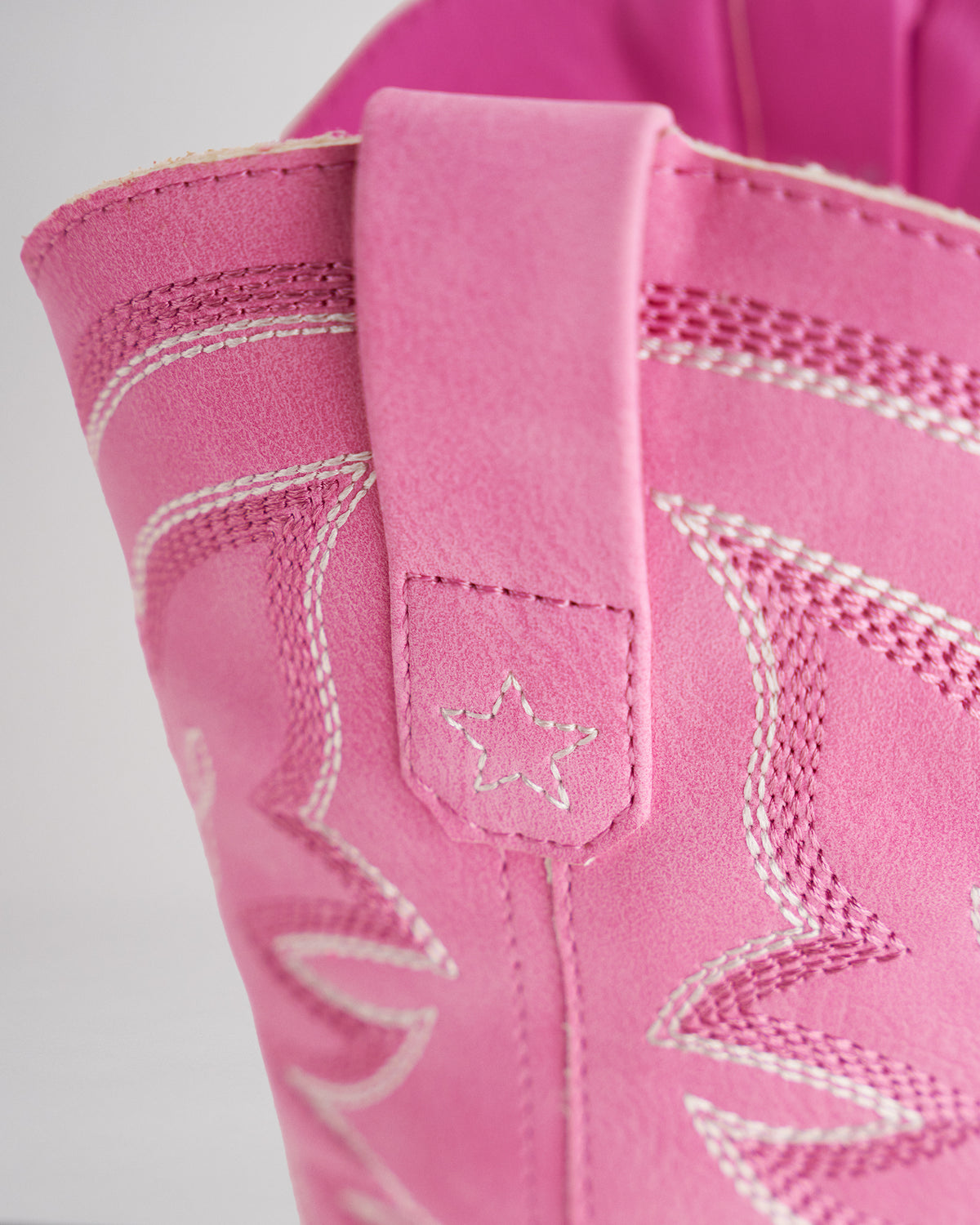 Close-up of the pink cowboy boot pull tab with star embroidery and white western stitching