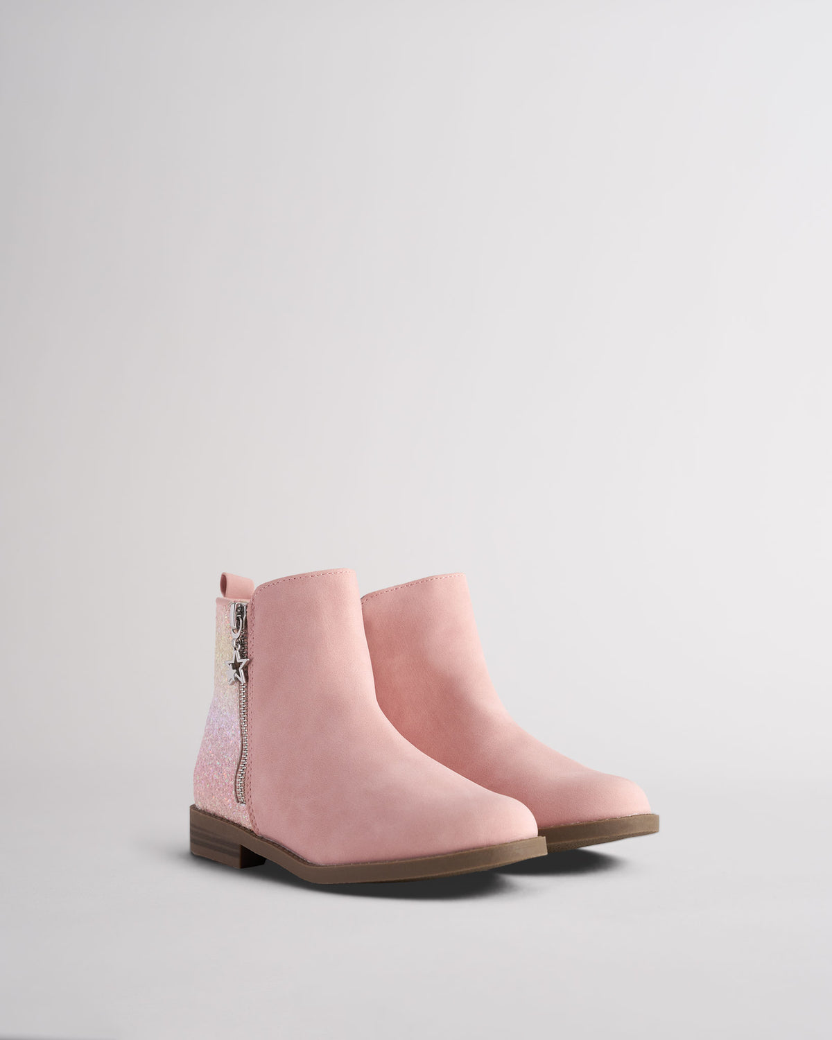 Pair of girls pink ankle boots with glitter heel detail and star charm zippers, angled front view showing round toe
