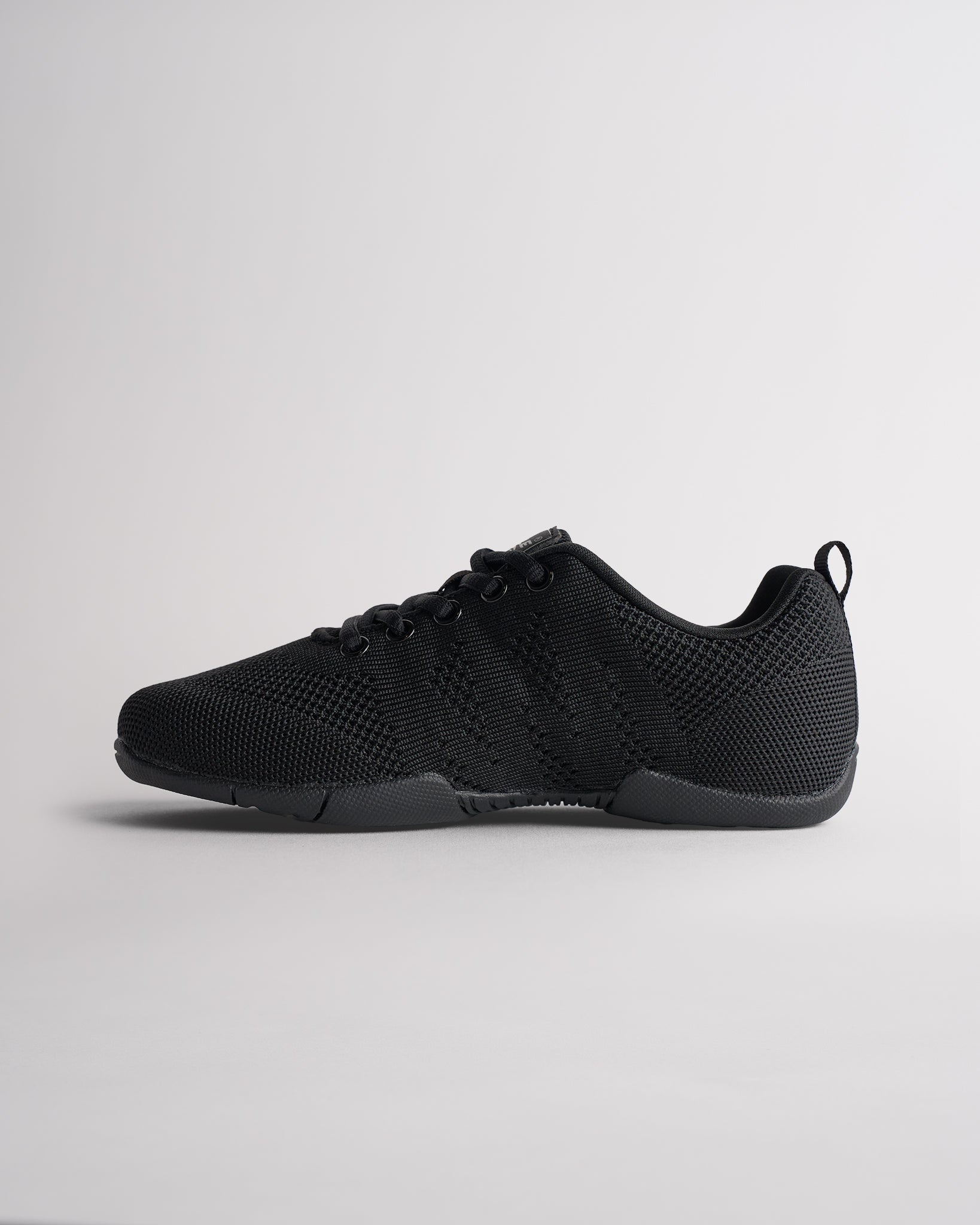 Angled view of black cheer shoes for girls showing breathable knit texture and flexible sole