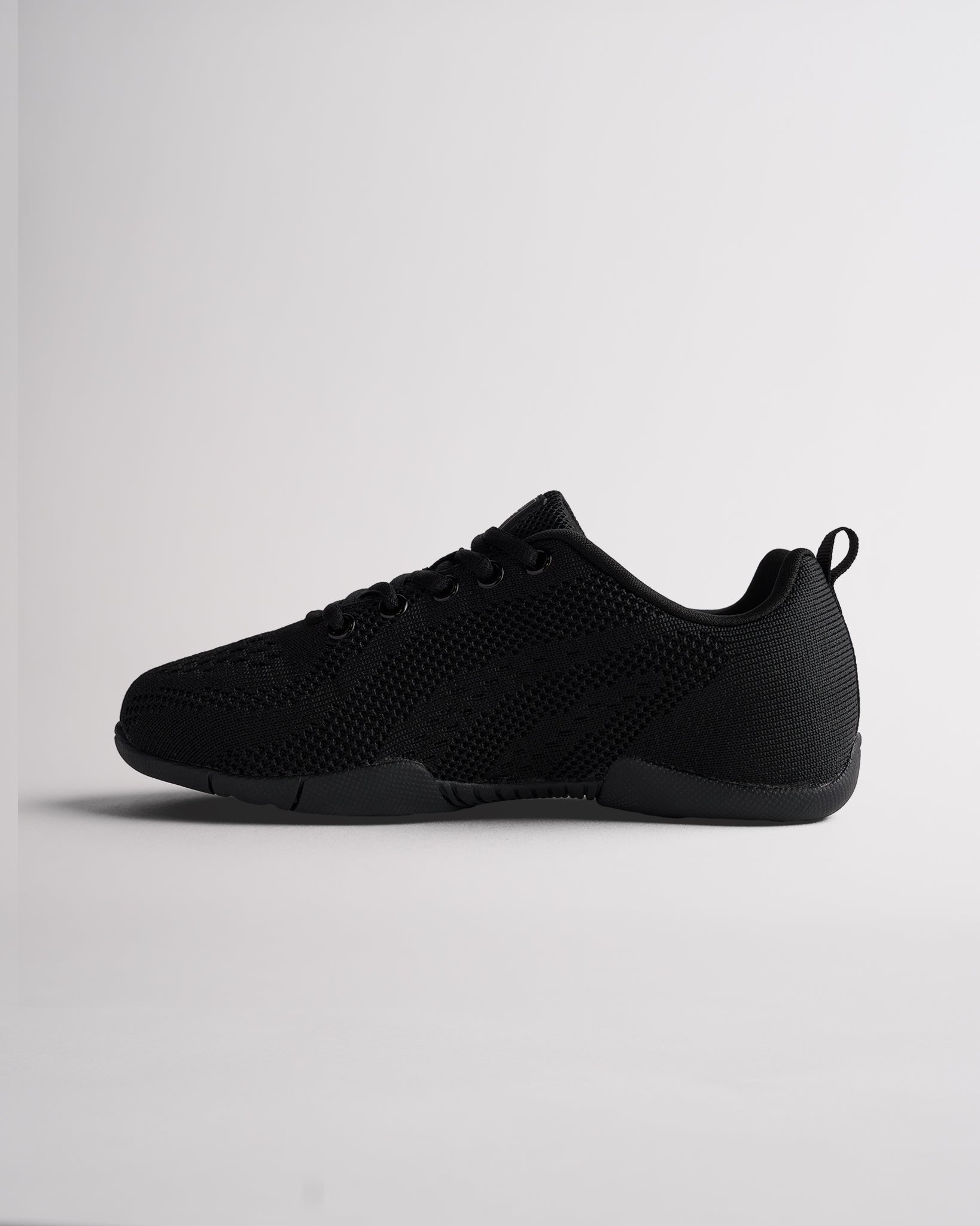 Angled view of black cheer shoes for girls showing flexible sole and textured knit