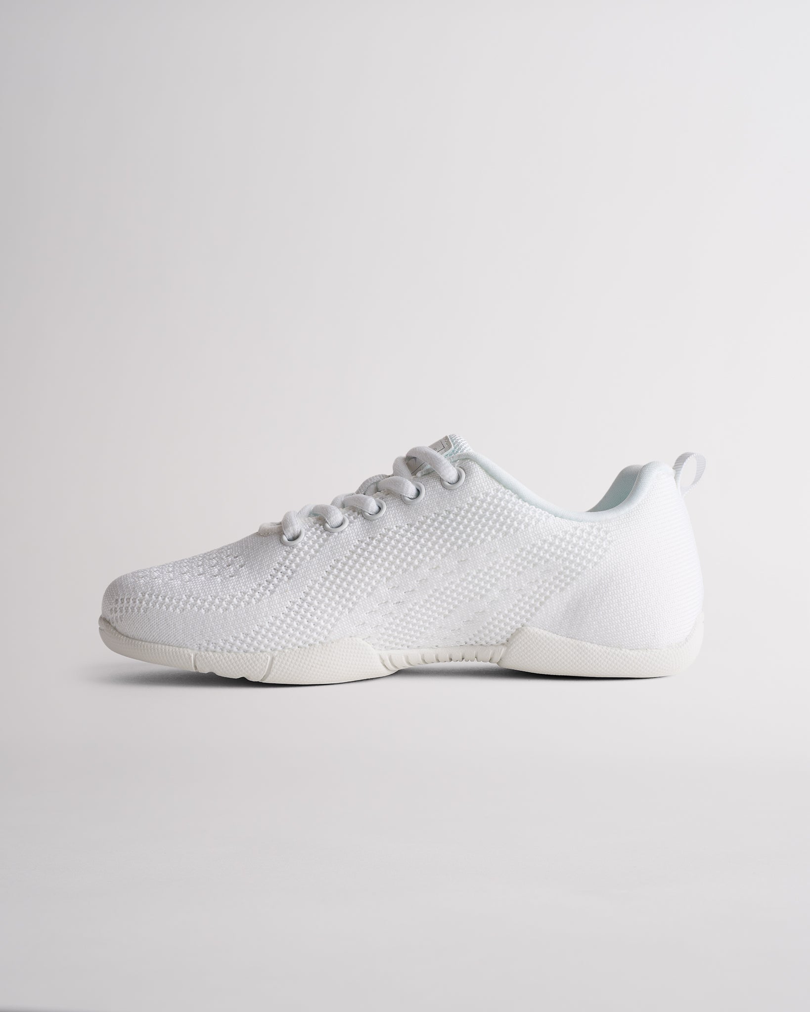 Angled view of white cheer shoes for girls showing flexible sole and textured knit