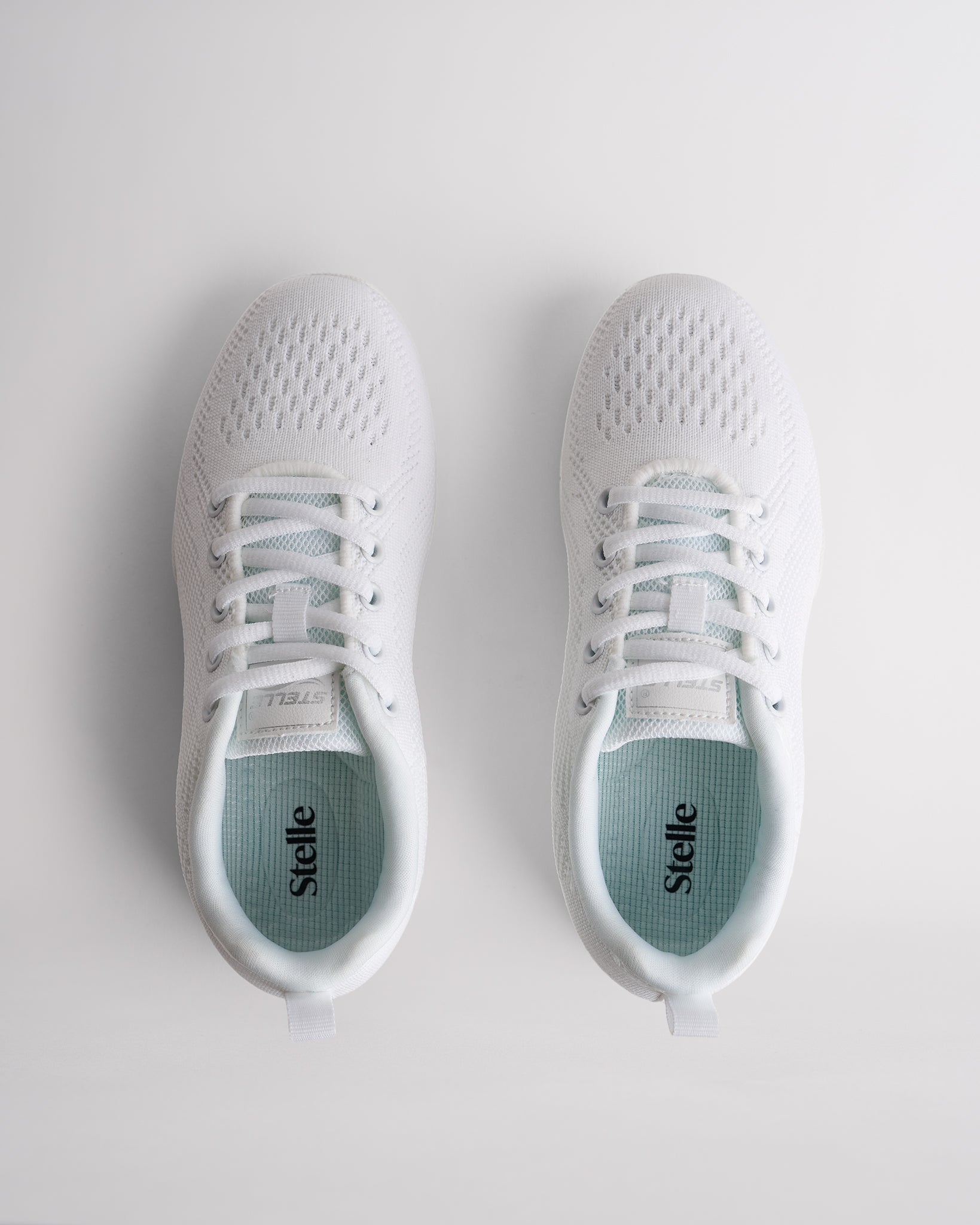 Top view of white lace-up cheer shoes with cushioned interior and Stelle branding