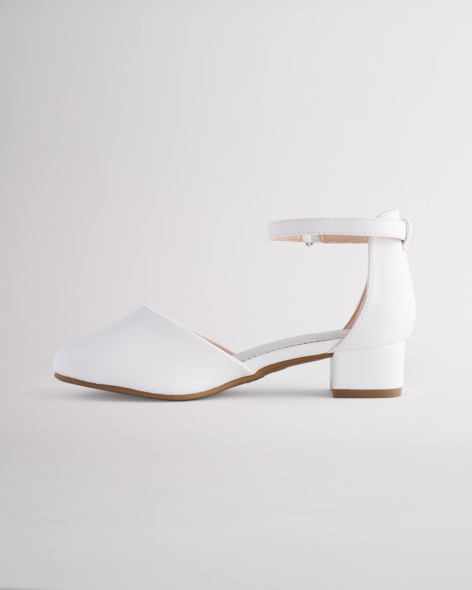Girls’ white dress shoes with a low block heel and ankle strap.