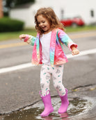 Child in colorful raincoat and pink boots playing in a puddle