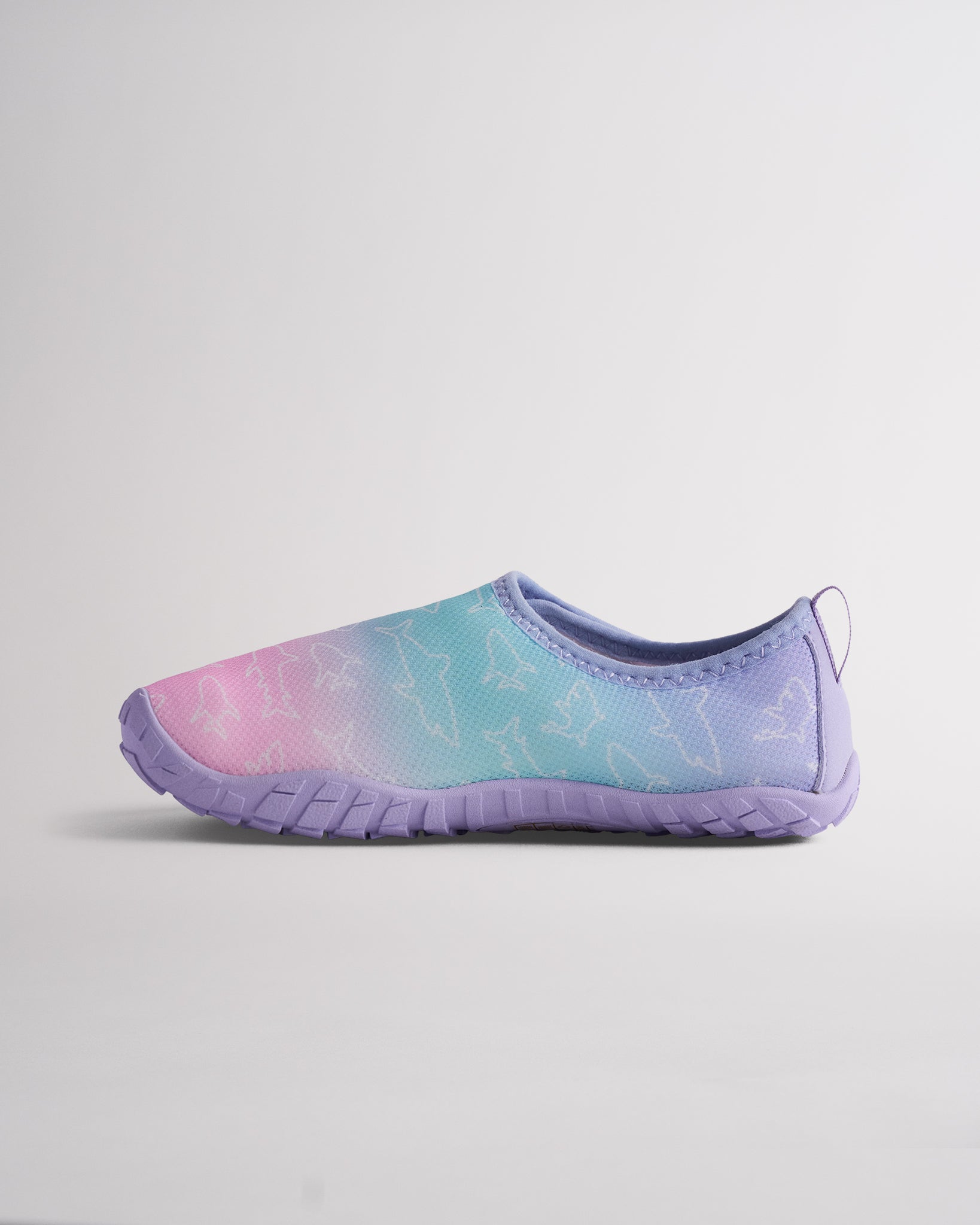 Side view of Kids StelleMesh water shoe showing the pink and blue ombre print, flexible slip-on design, and packable barefoot-inspired shape.