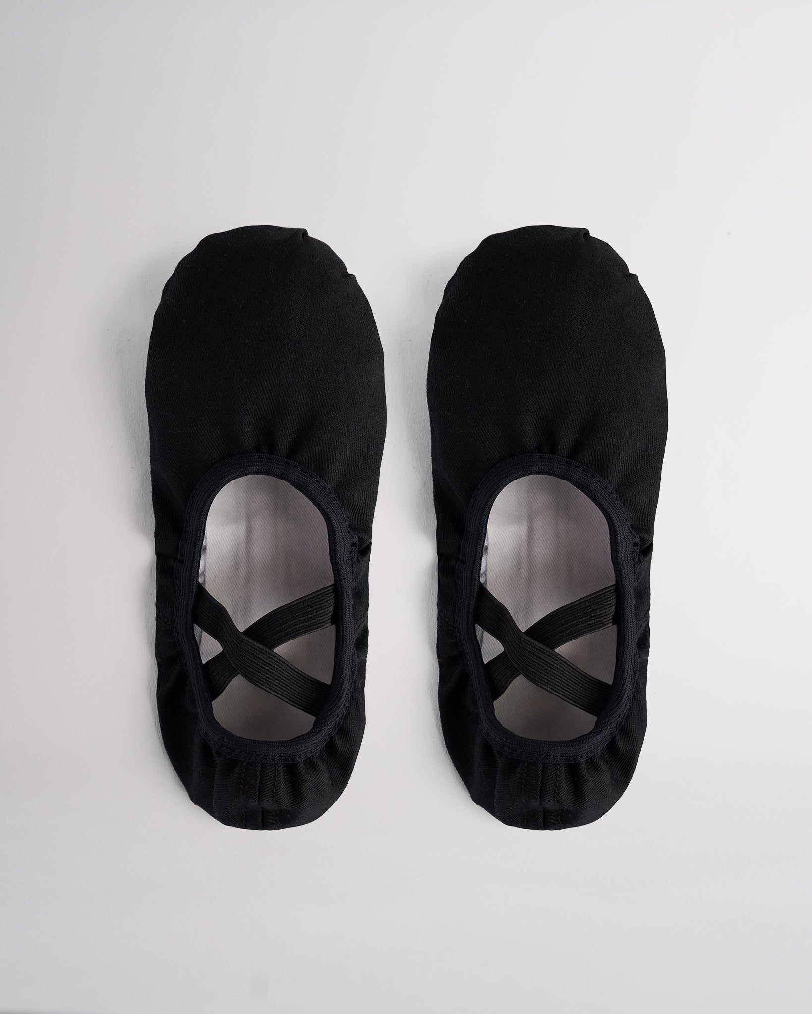 Pair of black kids stretch canvas ballet shoes with cross elastic straps, breathable canvas uppers, and split sole design.
