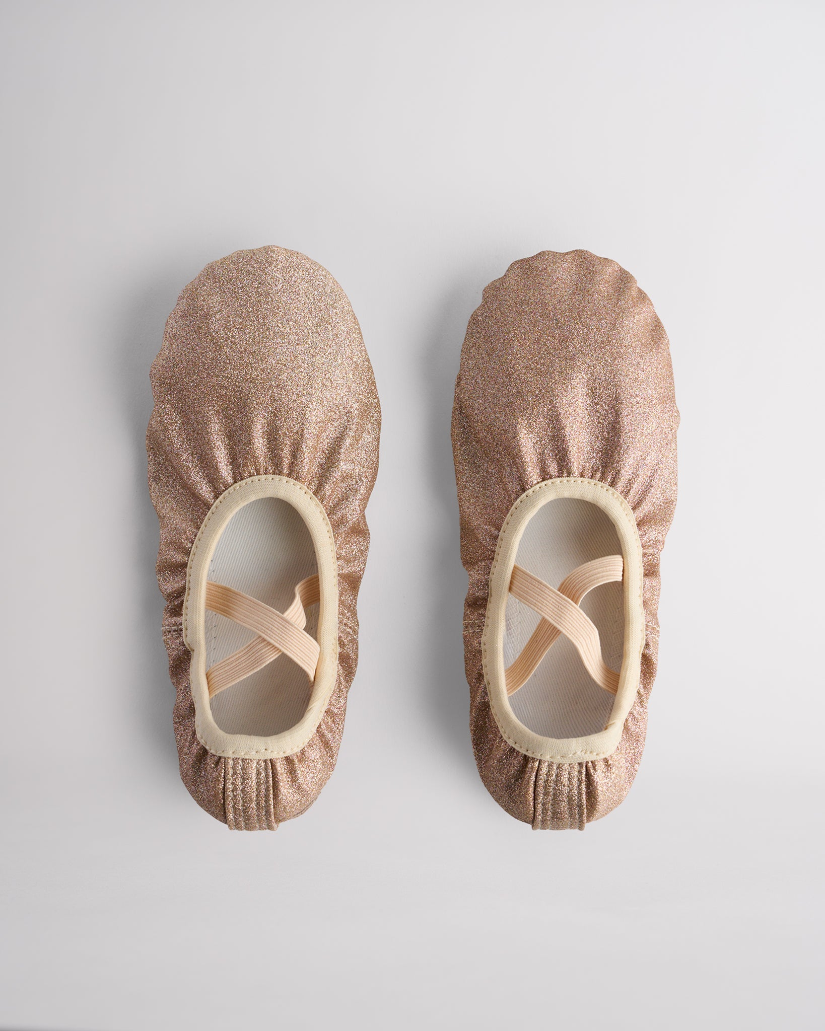 Kids glitter ballet shoes in gold glitter with crisscross elastic straps, top view