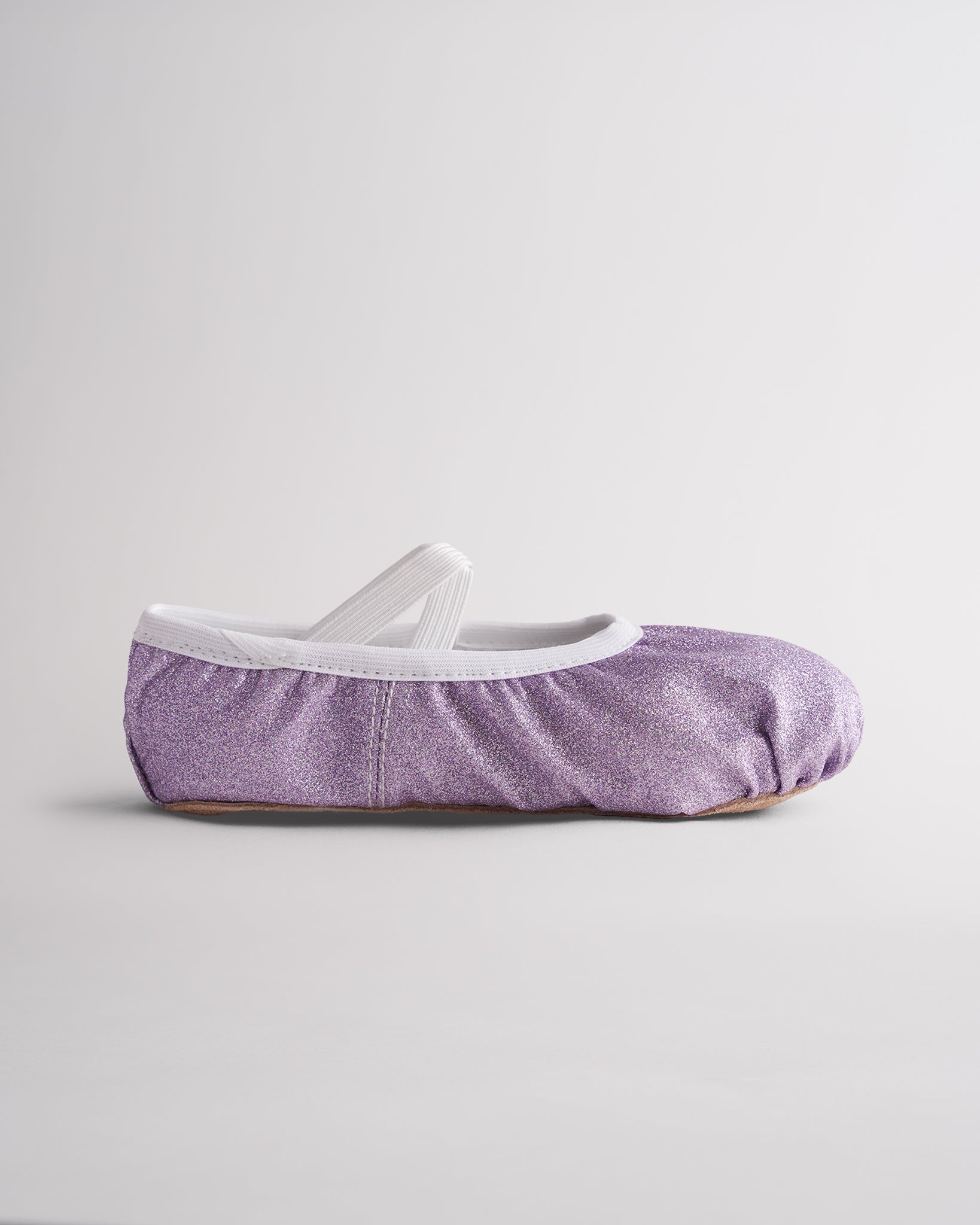 Kids glitter ballet shoes in purple glitter with elastic straps, side view