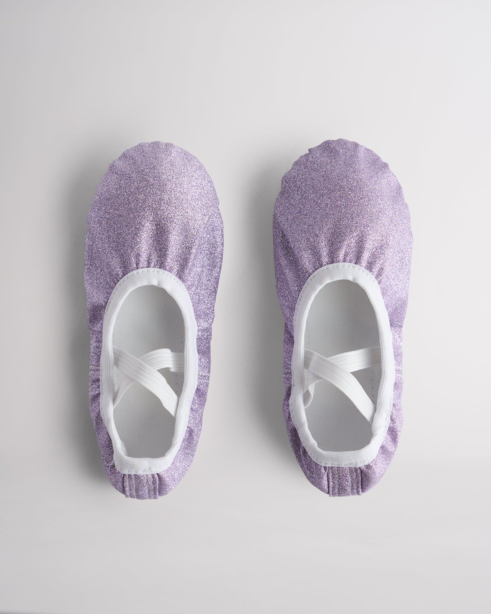 Kids glitter ballet shoes in purple glitter with crisscross elastic straps, top view