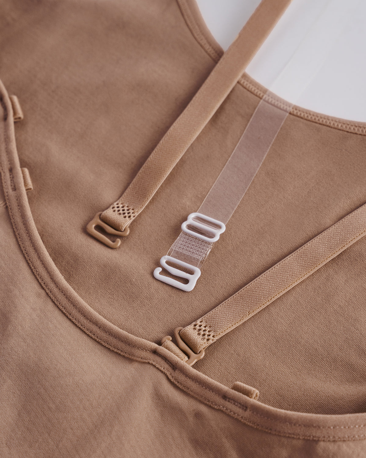Close-up of Warm Tan girls camisole leotard showing adjustable multi-way straps and smooth stretch fabric for costume layering.