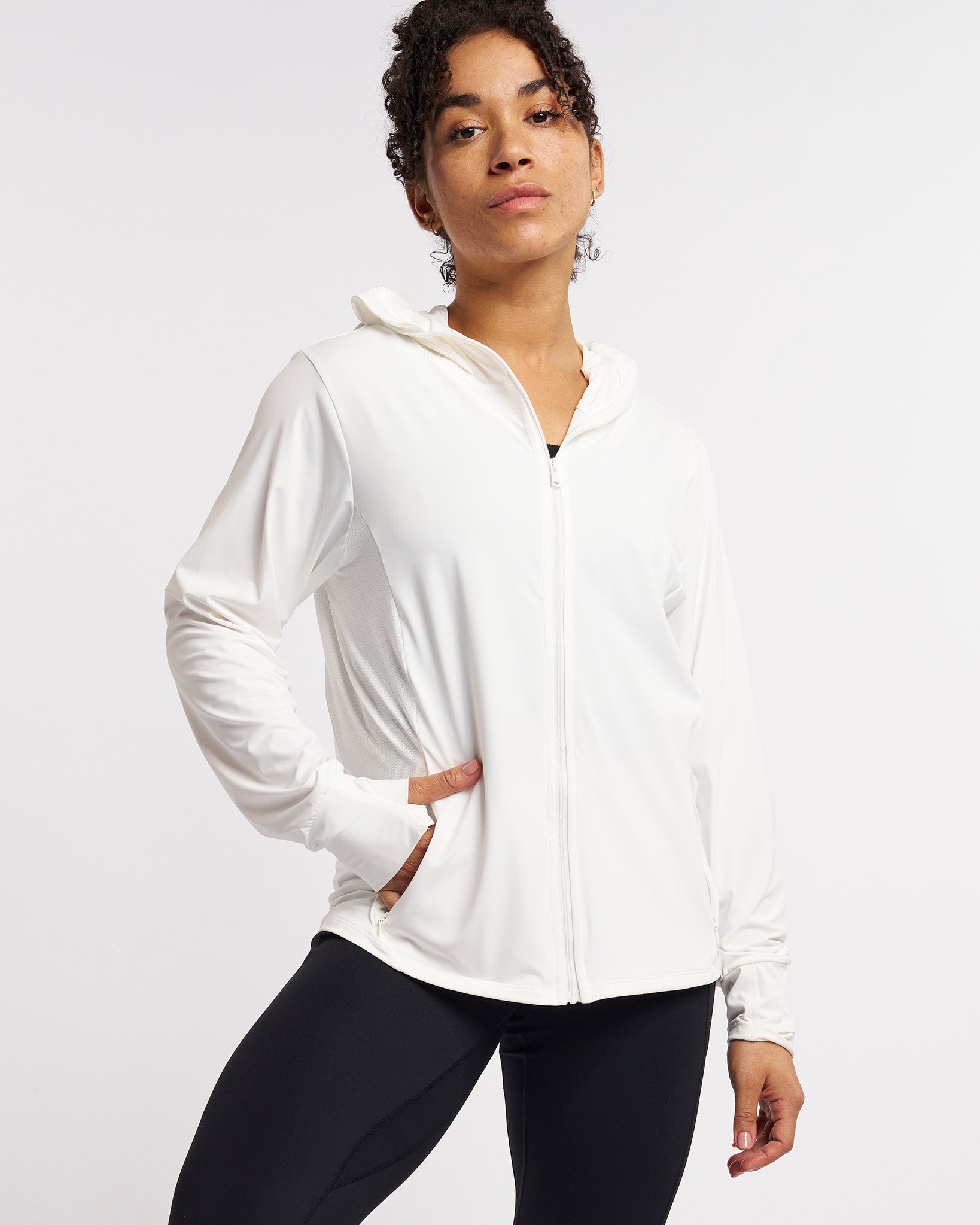 Woman wearing white UV-protective jacket with zip front, hood, and mesh side panels for breathable sun protection.