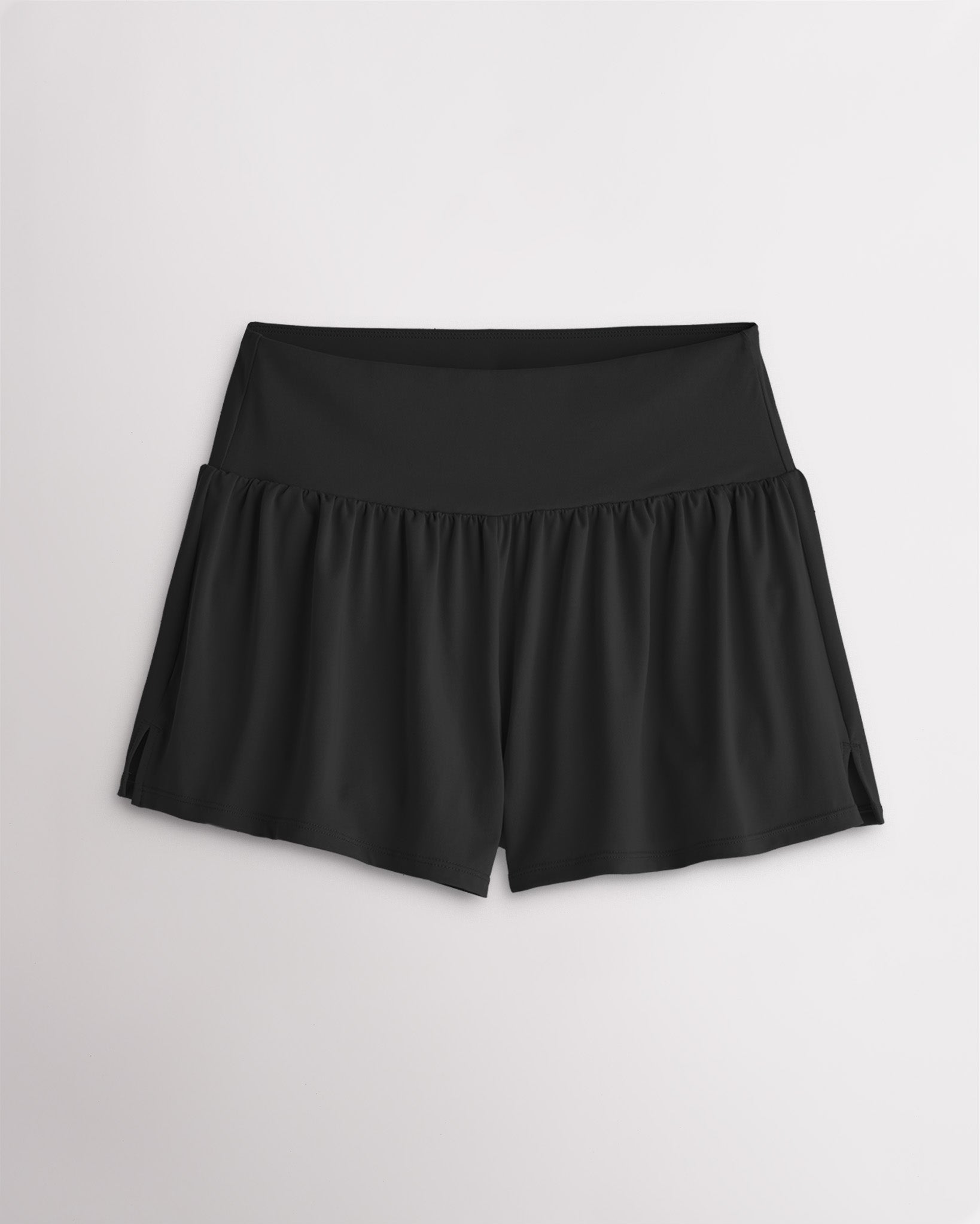 Women’s black 2-in-1 high waisted athletic shorts with a flowy outer layer, built-in shorts, and side slit detail.
