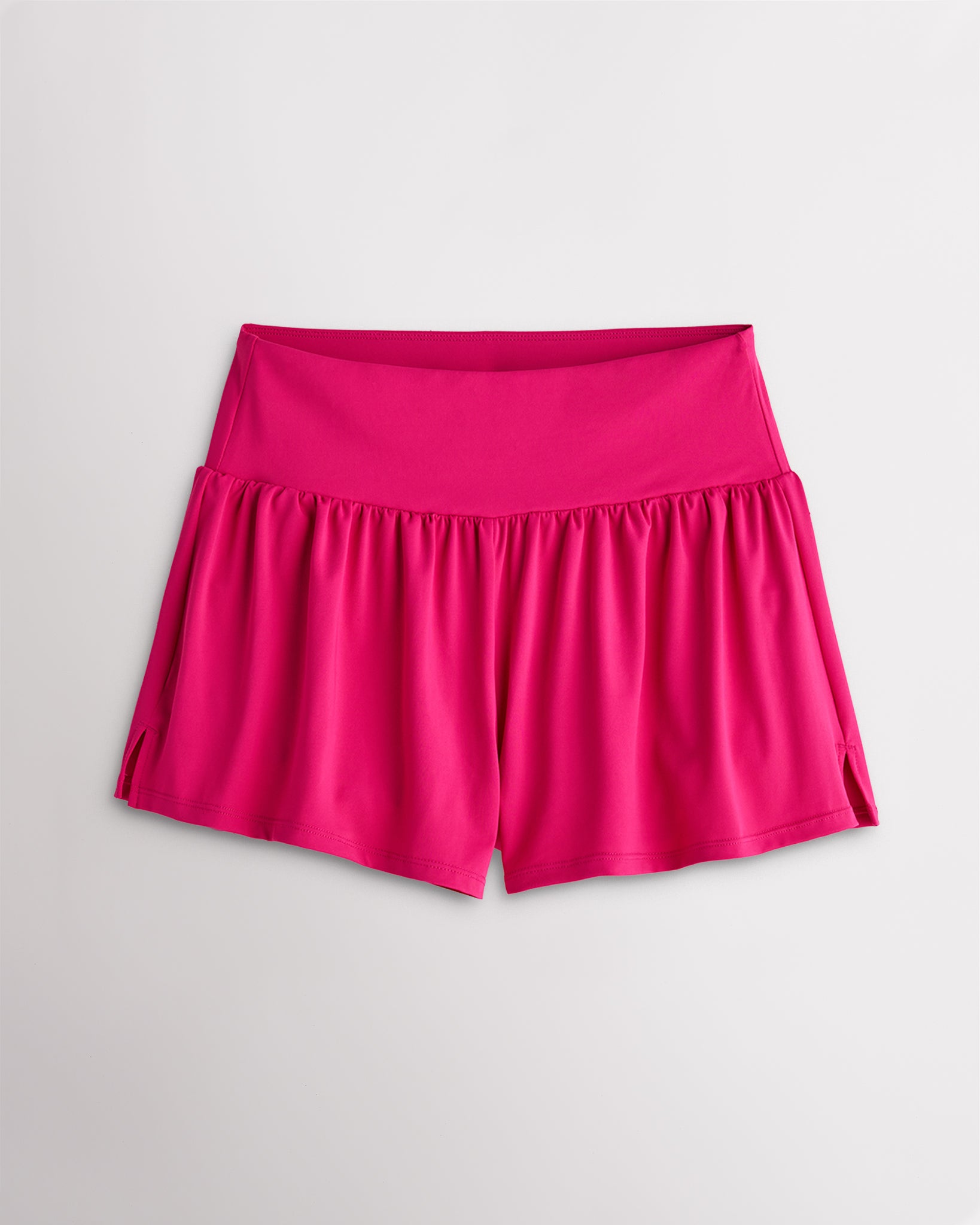Women’s dreamhouse pink 2-in-1 high waisted athletic shorts with a flowy outer layer, built-in shorts, and side slit detail.