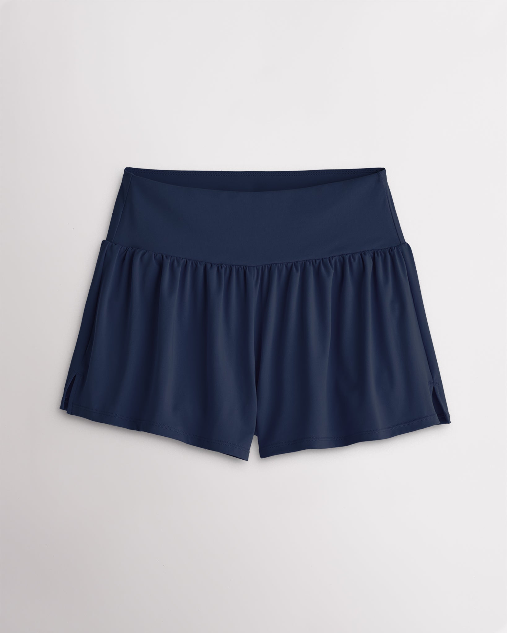 Women’s navy 2-in-1 high waisted athletic shorts with a flowy outer layer, built-in shorts, and side slit detail.