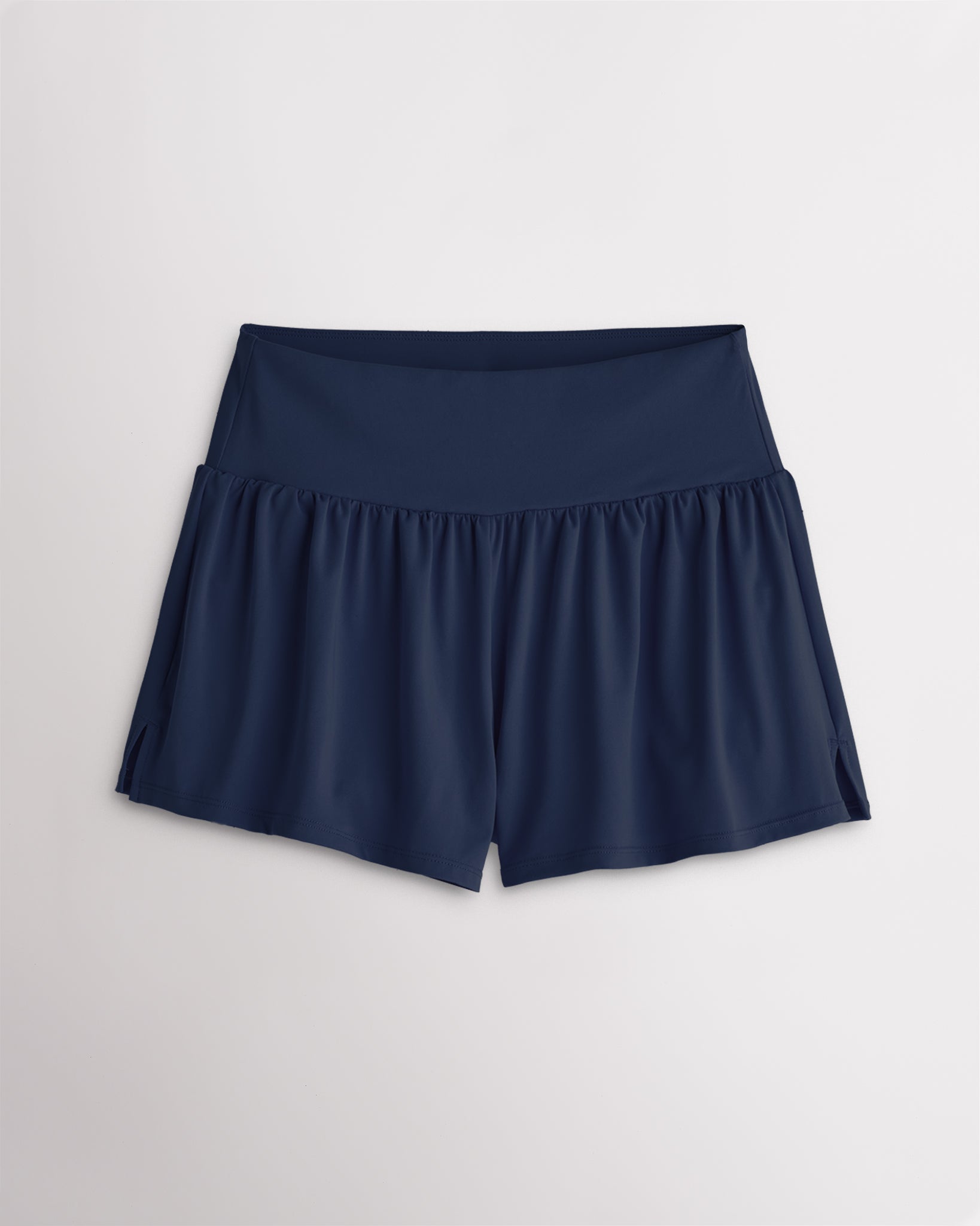 Women’s navy 2-in-1 high waisted athletic shorts with a flowy outer layer, built-in shorts, and side slit detail.