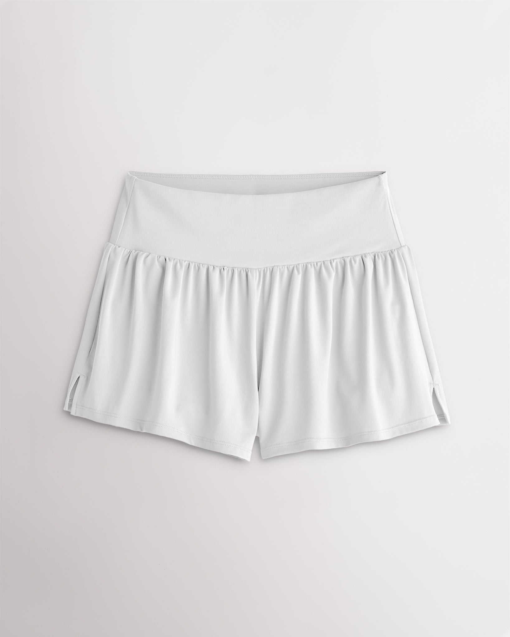 Women’s white 2-in-1 high waisted athletic shorts with a flowy outer layer, built-in shorts, and side slit detail.