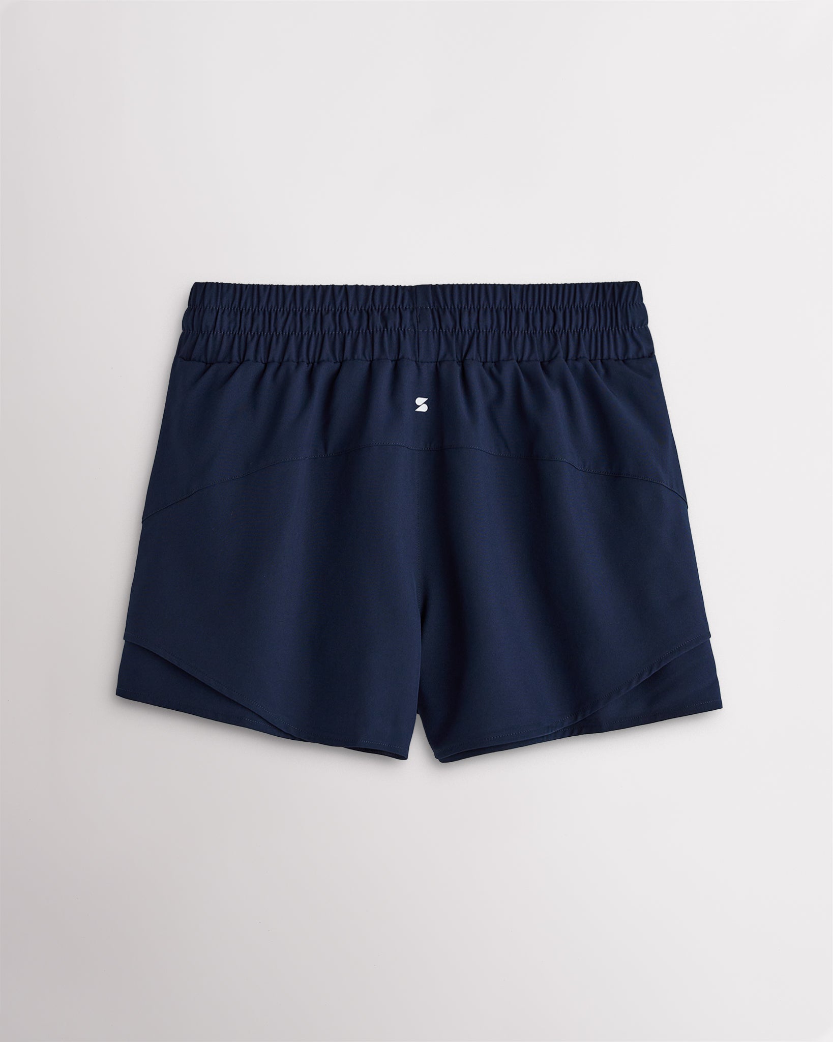Back view of women’s navy running shorts with a high-rise elastic waistband and layered hem design.