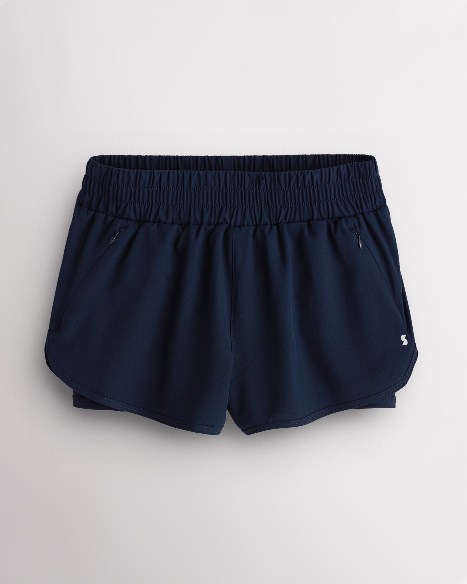 Navy Stelle RushMode 2-in-1 running shorts with wide elastic waistband, zipper pockets, inner shorts lining, and curved dolphin hem.