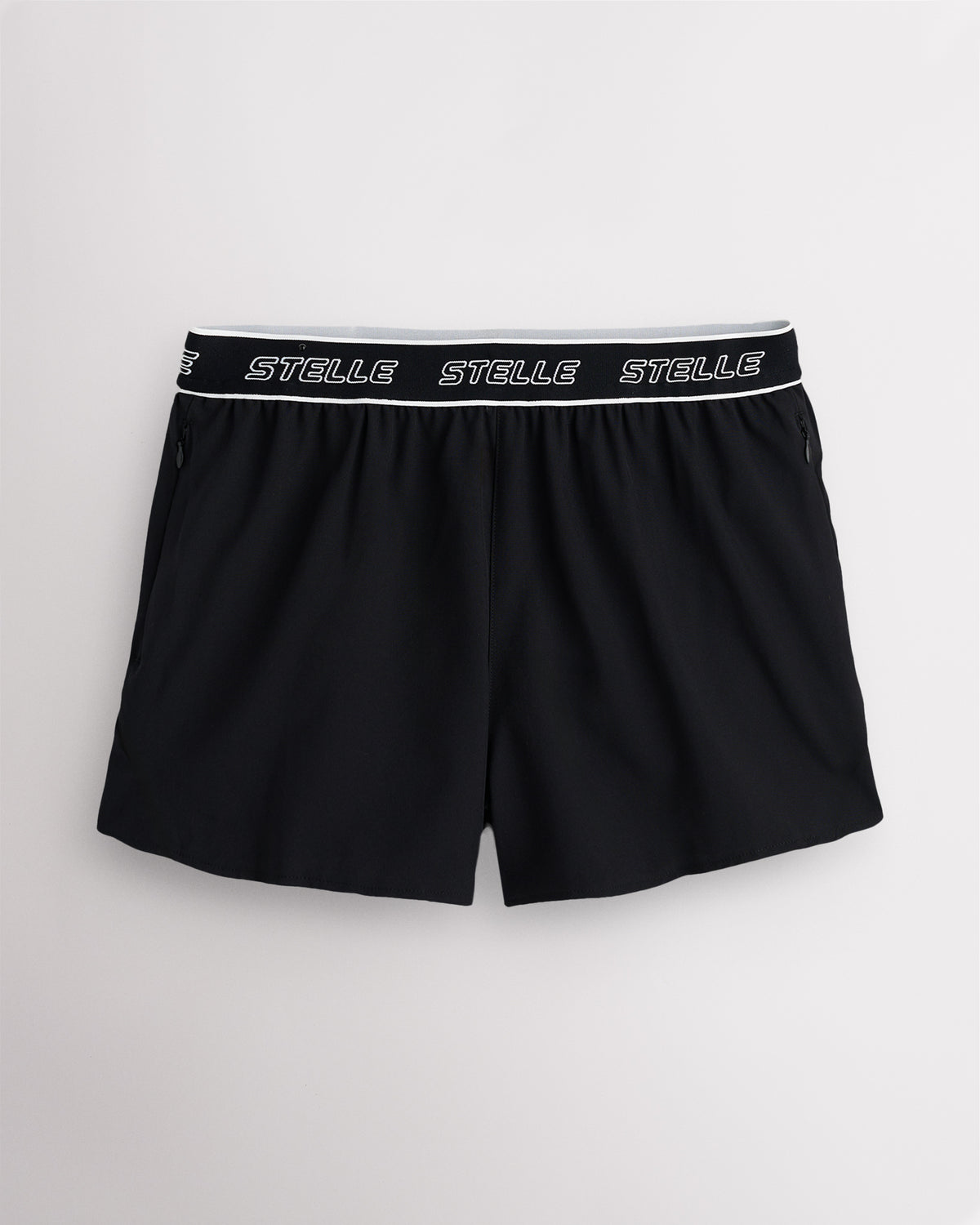 Black Stelle women's running shorts with a white logo waistband, laid flat on a grey background.